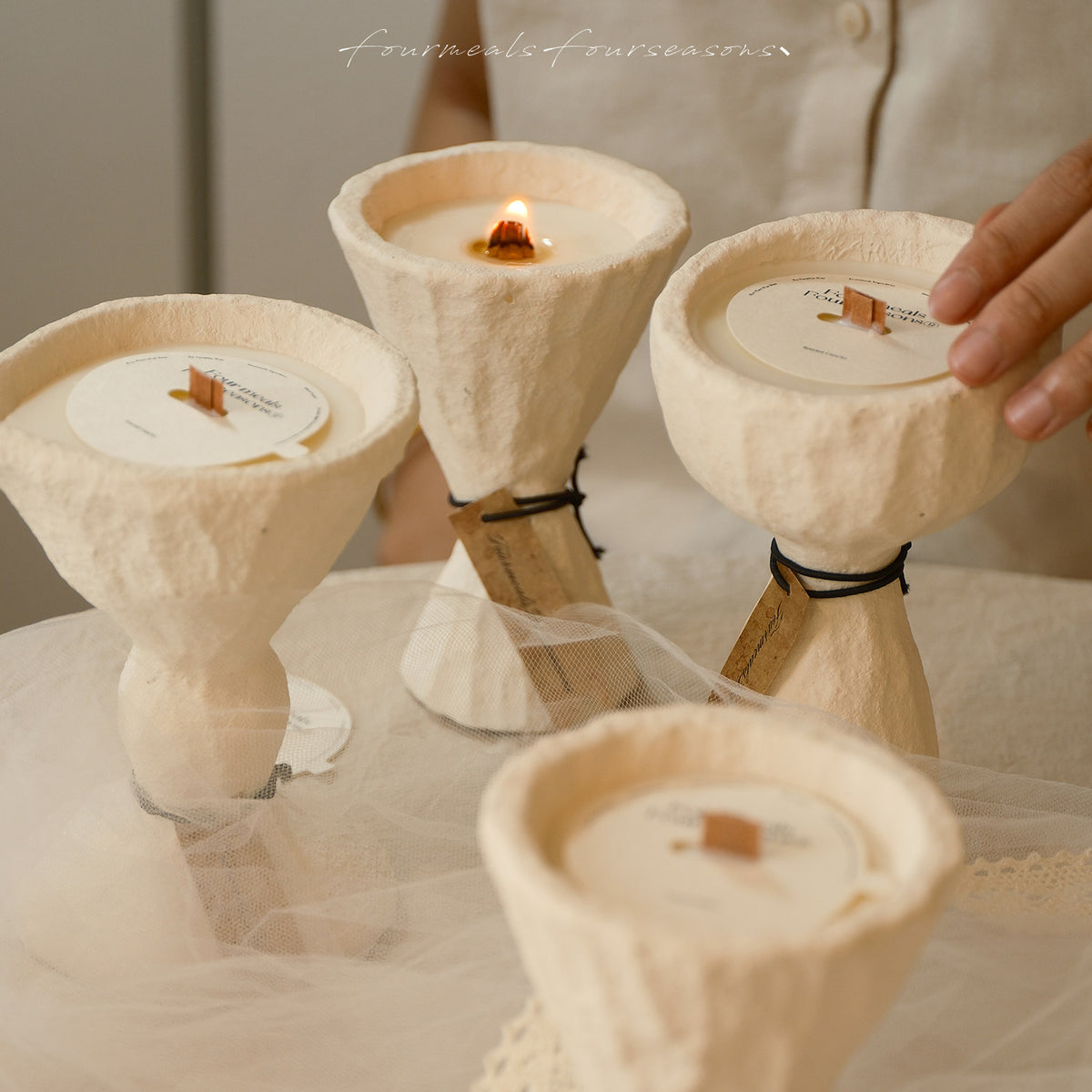 Four white sculptural cement candles with one candle lit