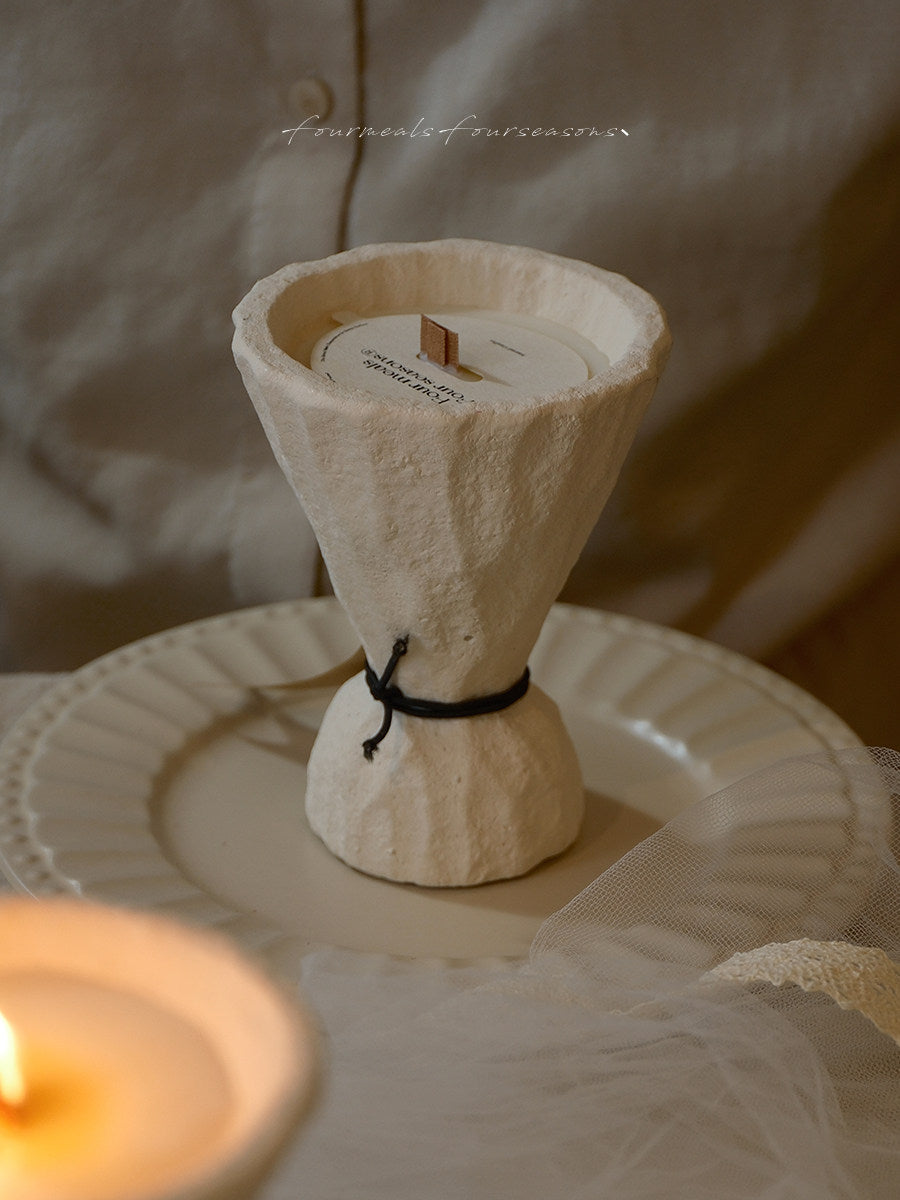 Textured hourglass-shaped soy candle in a warm styled setting