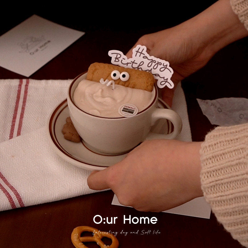 Hands arranging the Caramel Oat cup candle on a striped cloth