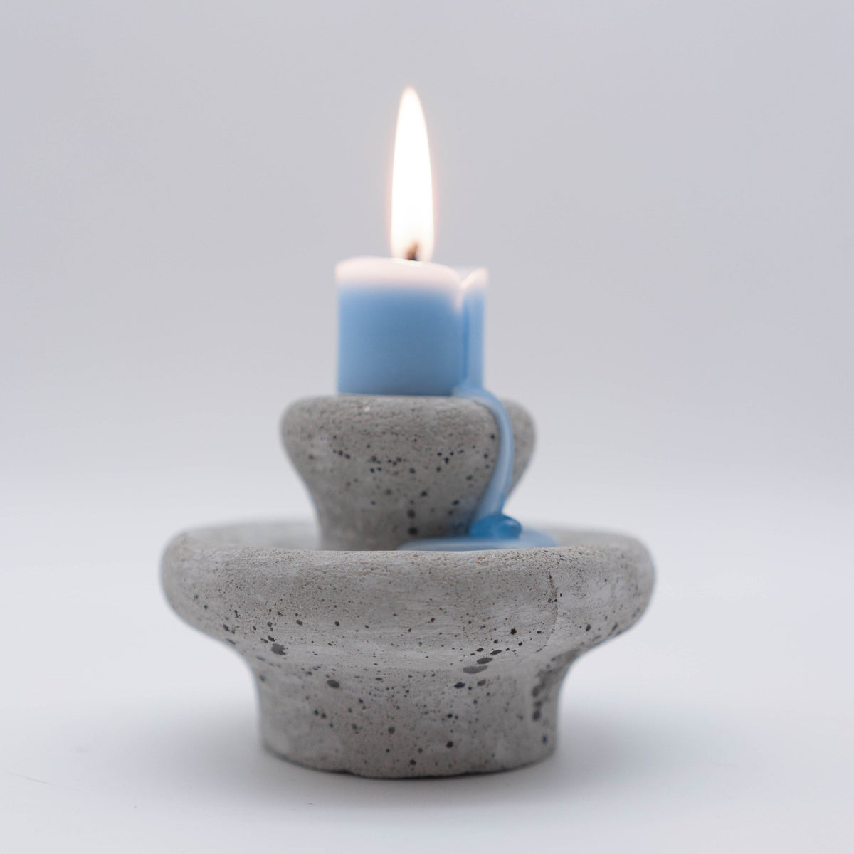 Lit Moon Spring candle viewed from the side on a soft white background