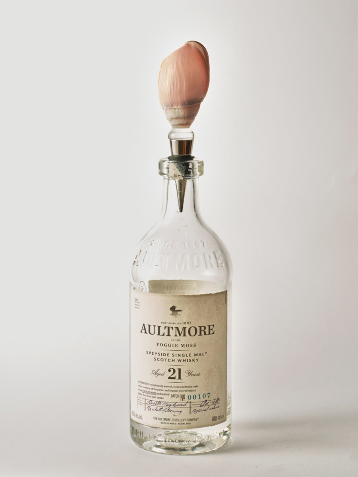 Blush pink seashell wine stopper in a clear whisky bottle