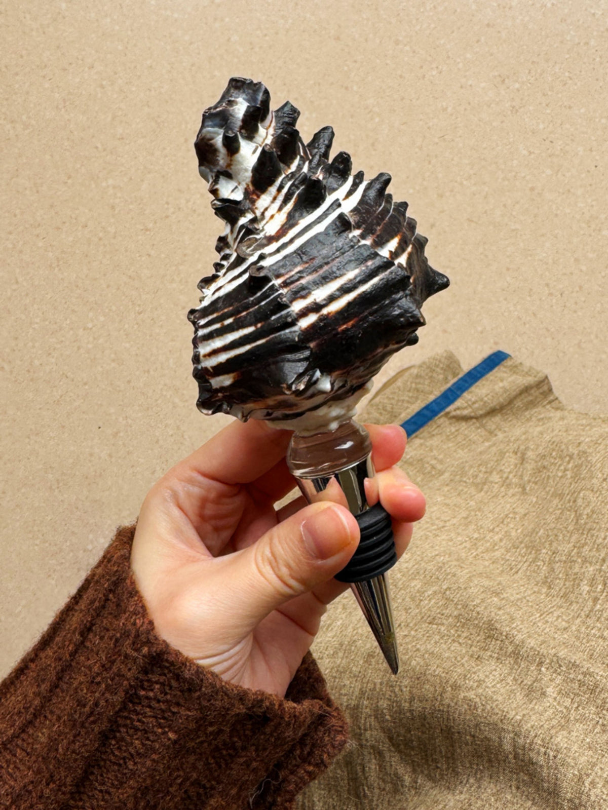 Hand holding a dark sculptural seashell wine stopper