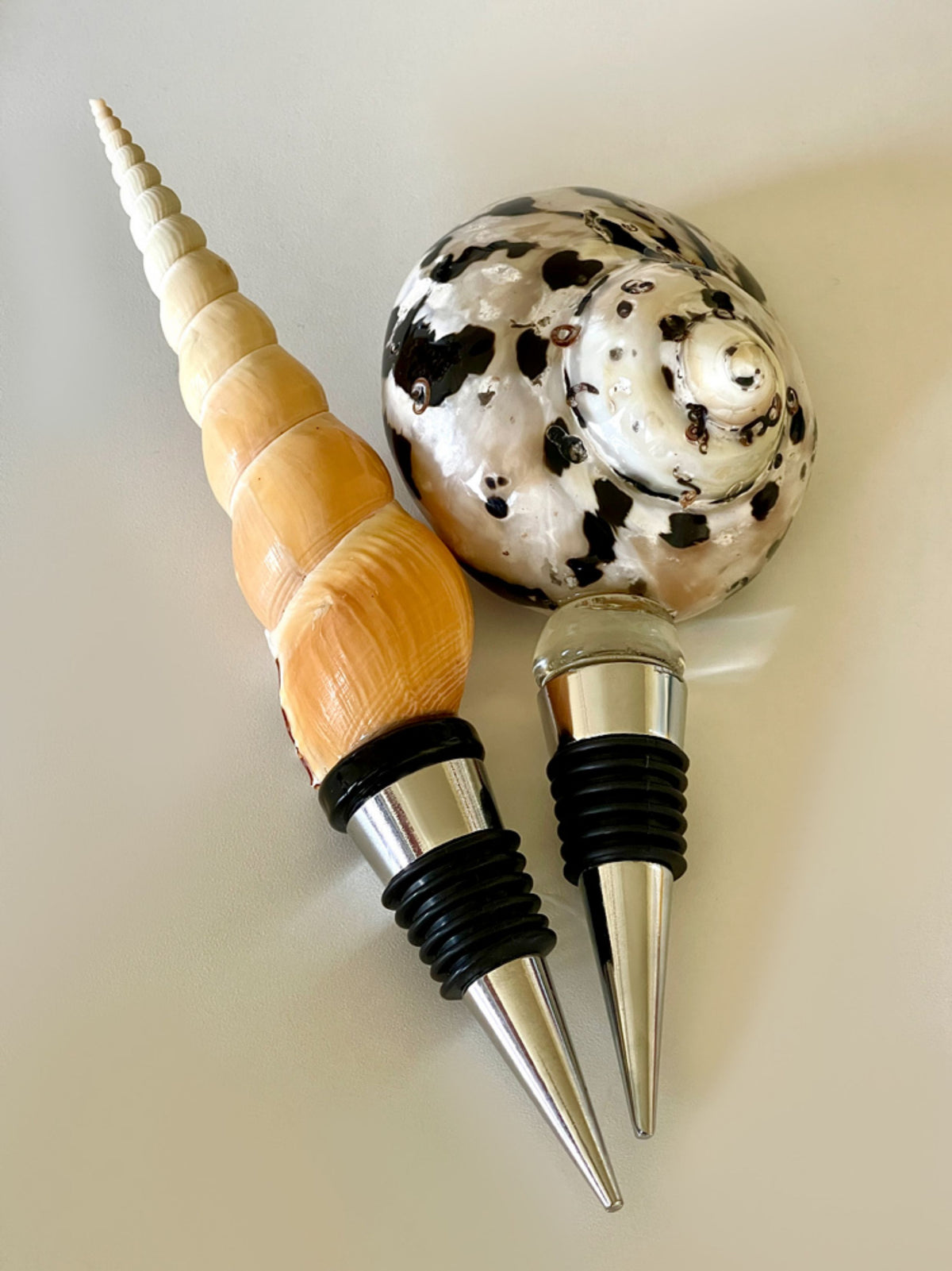 Two SoftServe seashell wine stoppers photographed on a cream background