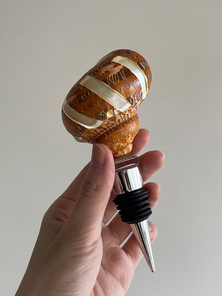 Hand holding an amber ridged seashell wine stopper