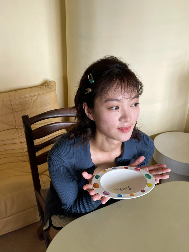 Woman holding an empty SoftServe colorful candy bean bowl while seated