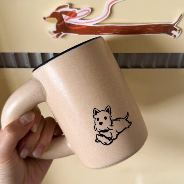 Hand holding a pink SoftServe cat ceramic mug