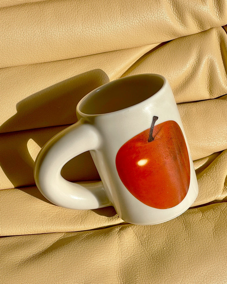 SoftServe red apple ceramic mug styled on gold fabric