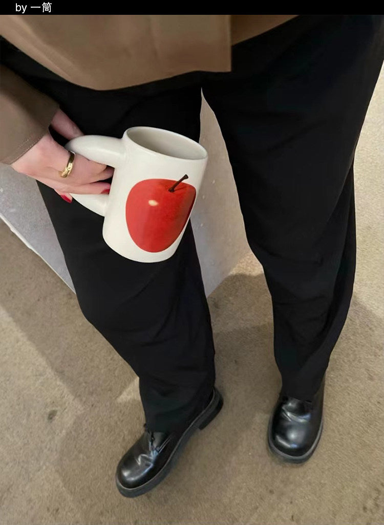 Person holding a SoftServe red apple ceramic mug outdoors