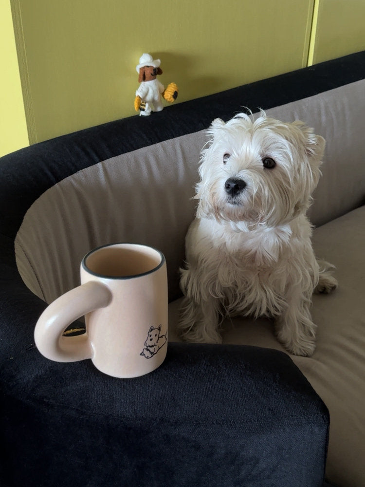 SoftServe pink character mug beside a small white dog on a sofa