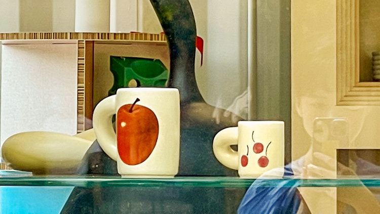 Three SoftServe illustrated ceramic mugs styled on a colorful table