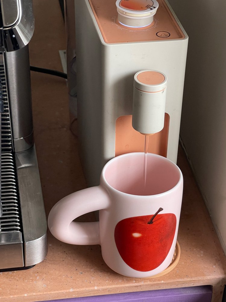 SoftServe red apple ceramic mug positioned under a coffee machine