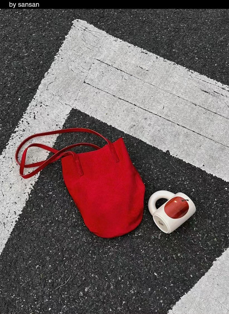 Small white SoftServe mug beside a red fabric tote on a gray carpet