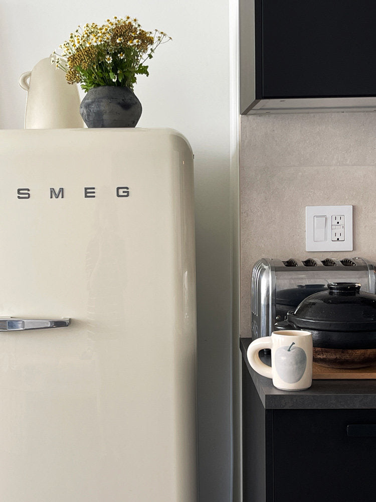 SoftServe white ceramic mug beside a coffee machine and cream refrigerator