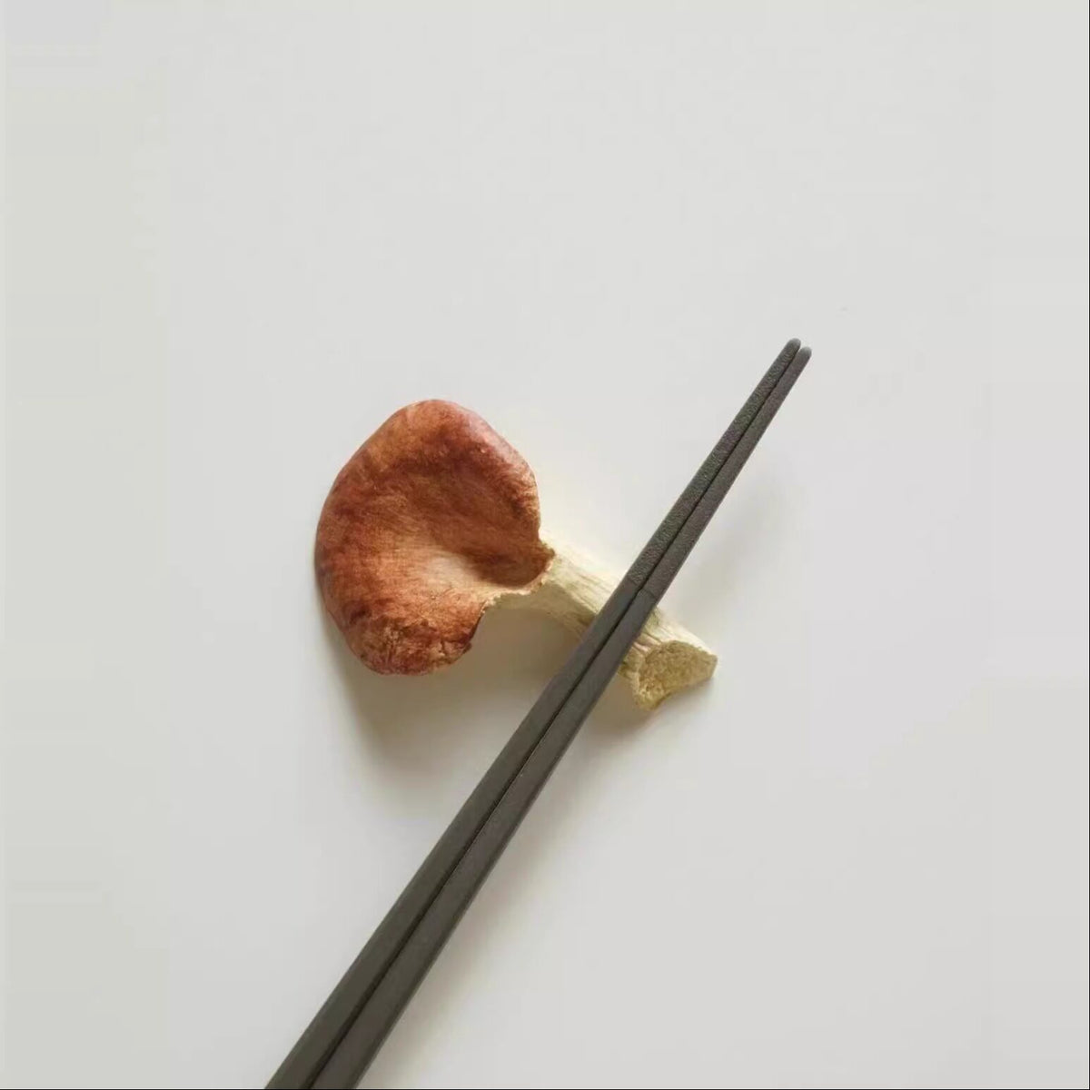 Chopsticks resting on a red-capped mushroom cutlery rest