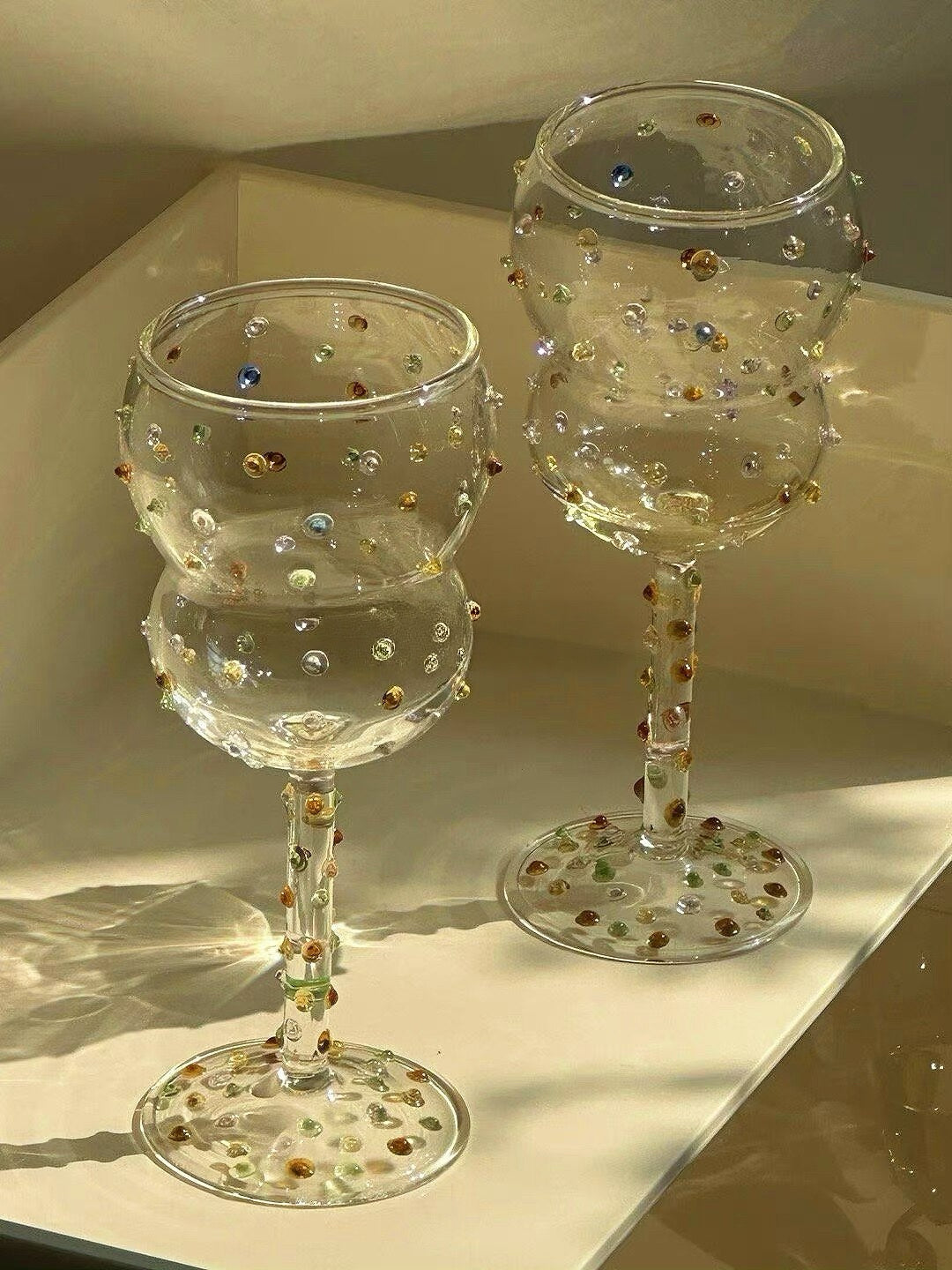 Two colorful gemstone wine glasses in warm natural light
