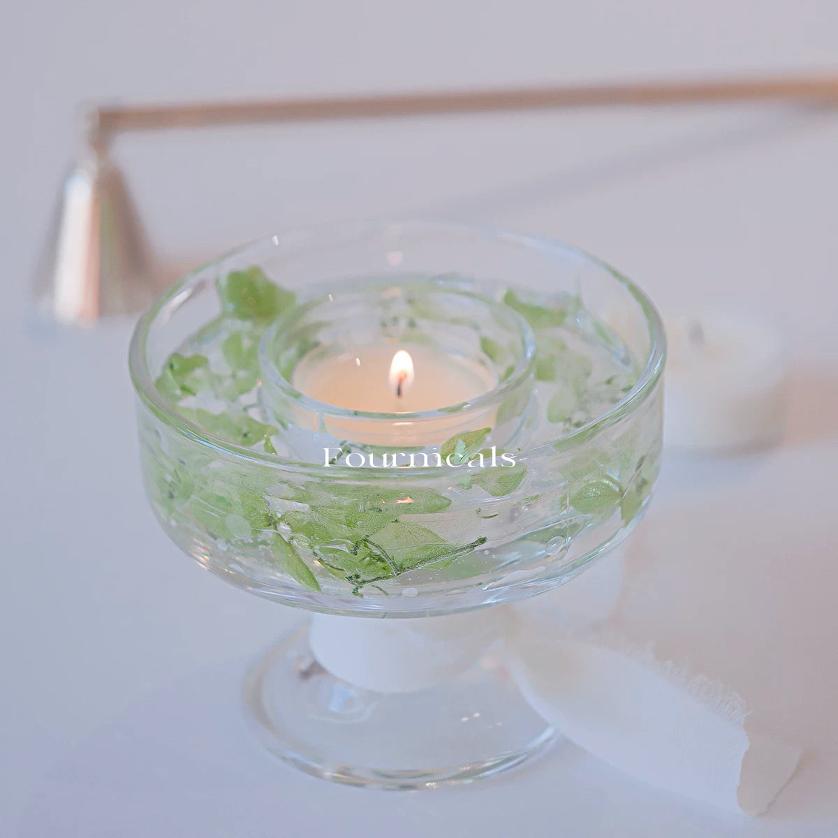 Green botanical glass candle holder in a soft interior scene