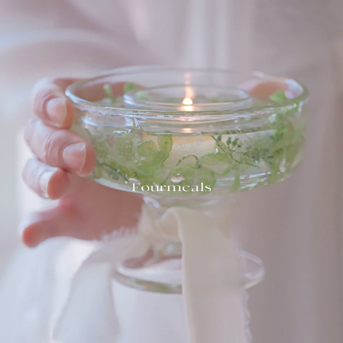Botanical glass tealight holder glowing in hand