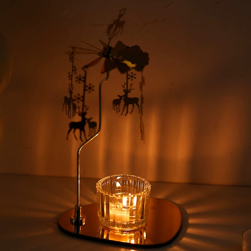 Golden deer candle carousel glowing beside a glass tealight holder